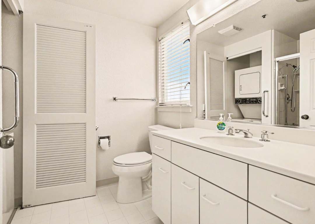 All white bathroom also including a stackable washer and dryer
