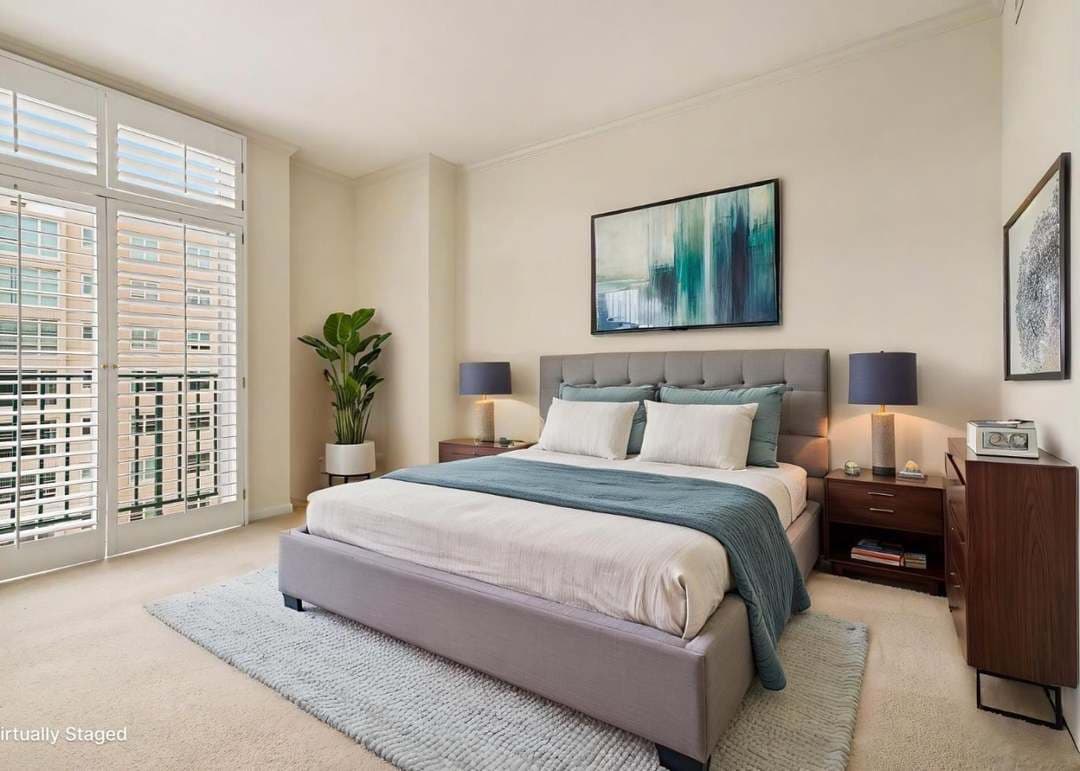 Condo bedroom with large windows and tastefully staged with large bed